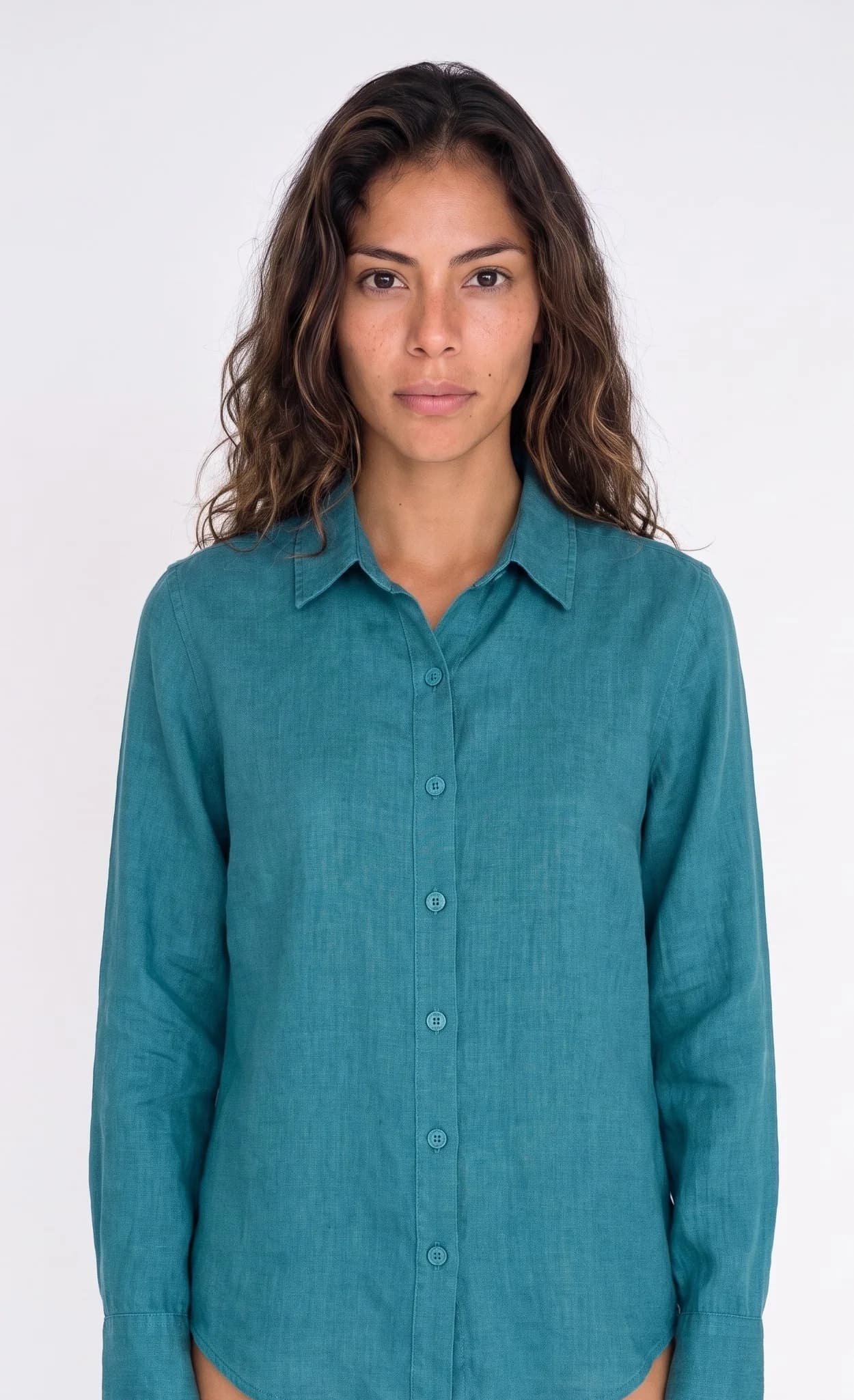 Modelo adulta de frente usando una blusa verde azulado que conserva seis botones, cuello en punta, mangas largas y ruedo curvo.